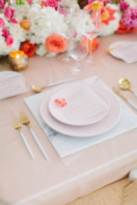 blush colored styled place setting with gold flatware and white marble charger