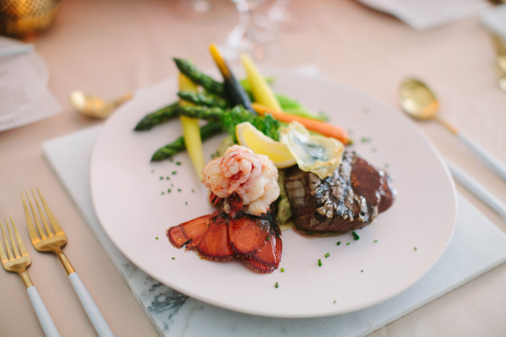 beautifully styled plate by Soiree Catering and Events, with beef tips, shrimp, lemon wedge, and roasted root vegetables