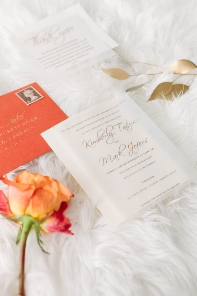 coral wedding stationery suite by The Taylored Design Co., flat lay on white flokati