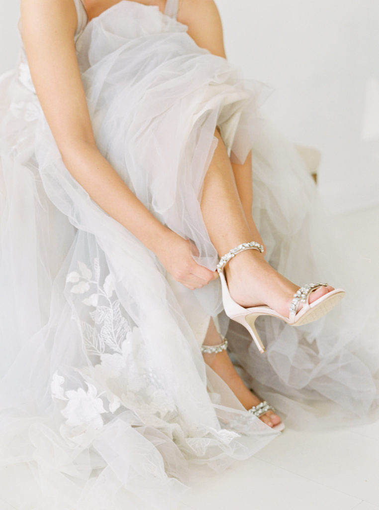 sitting bride showing off Badgley Mischka shoes