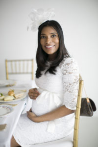 beautiful African American mother to be wearing white fascinator