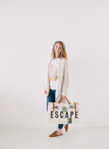 pretty blonde girl holding ESCAPE labeled old fashioned suitecase