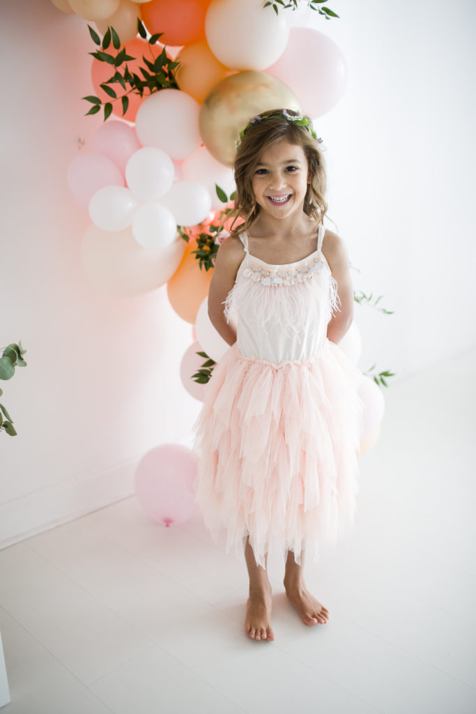 little girl wearing ballet dress, with balloon installation behind her