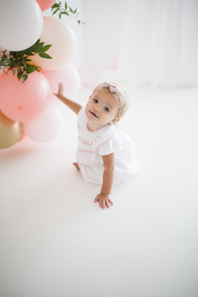 baby girl holding balloons