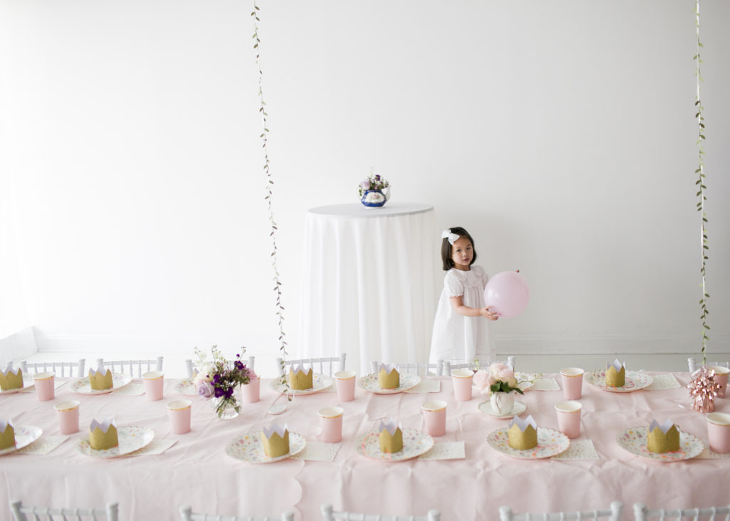 little girl holding a pink balloon, garden tea party tables in foreground